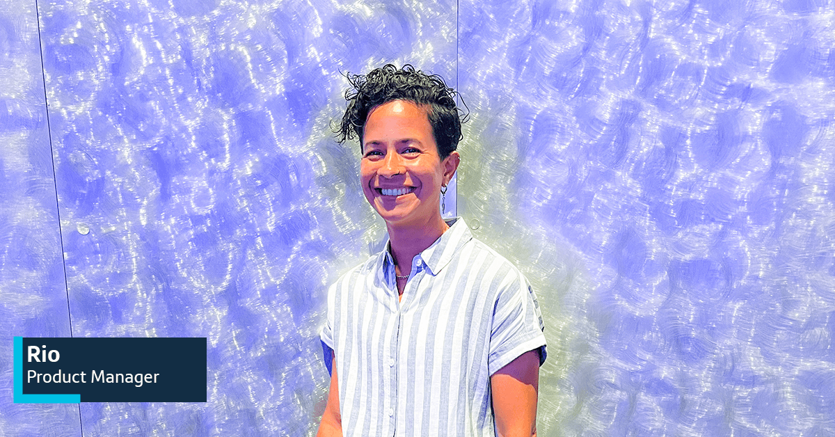 Capital One associate Rioi stands in front of a swirly purple wall smiling